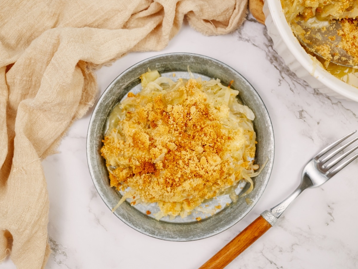 a bowl of cabbage casserole with a fork sitting on the side