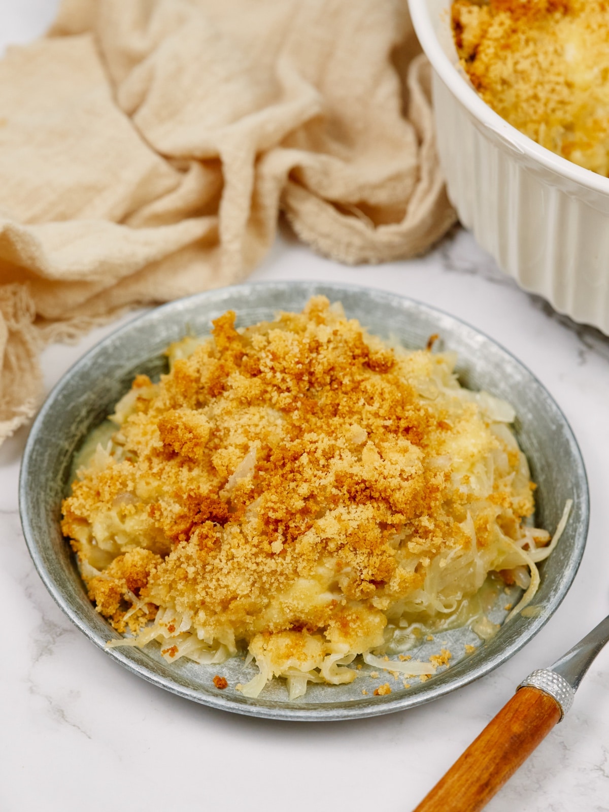 a bowl of cabbage casserole with a fork sitting on the side