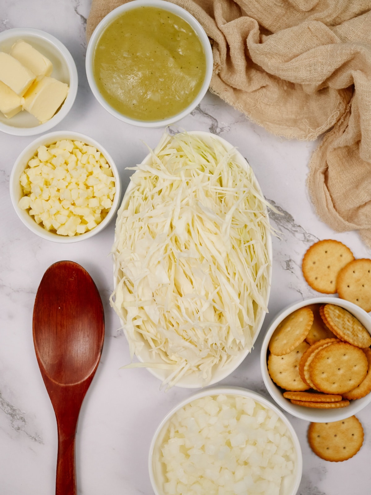 ingredients for cabbage casserole in small bowls with a wooden spoon sitting on the side