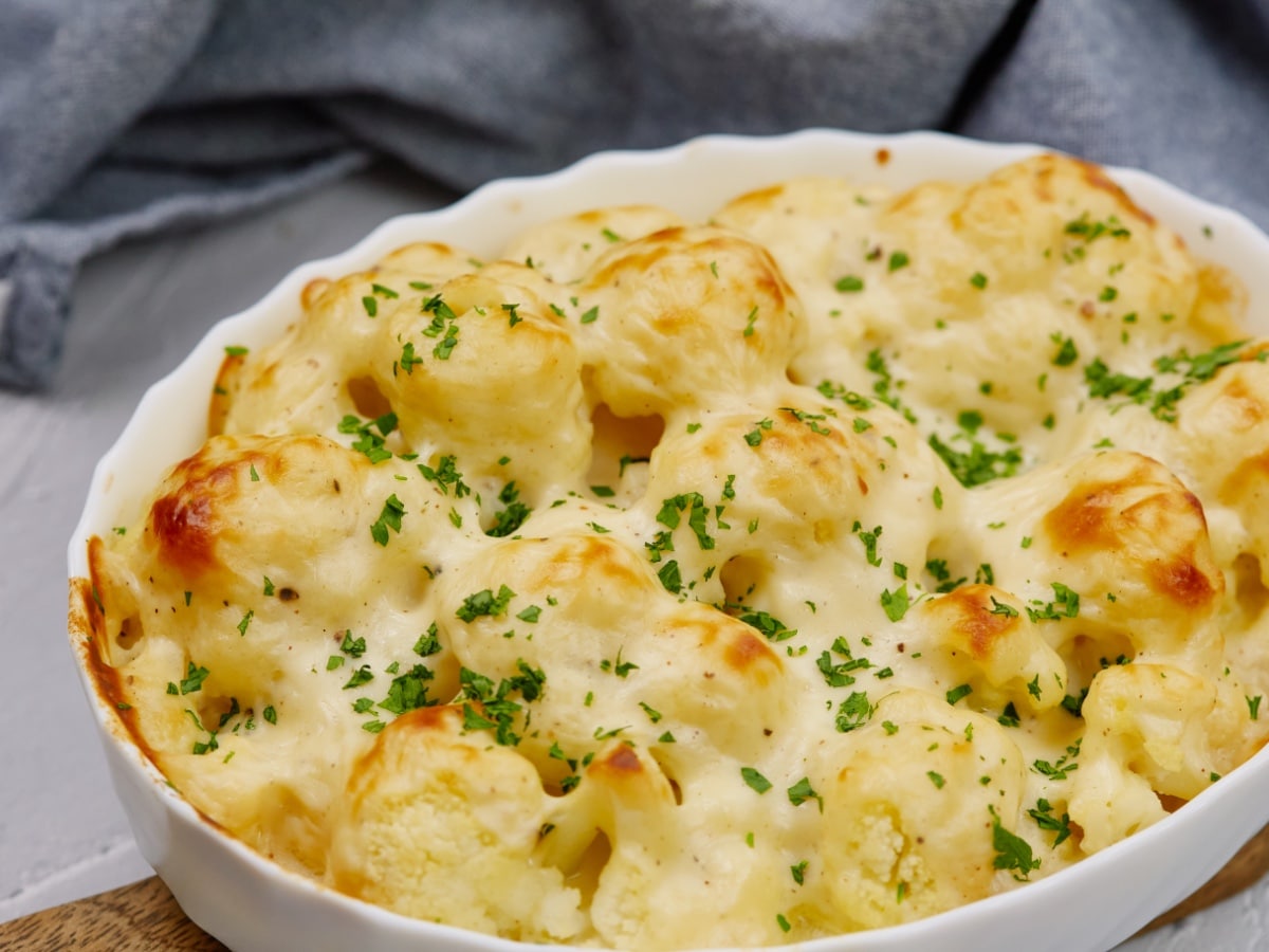 baked cauliflower casserole topped with minced chives in a white baking dish