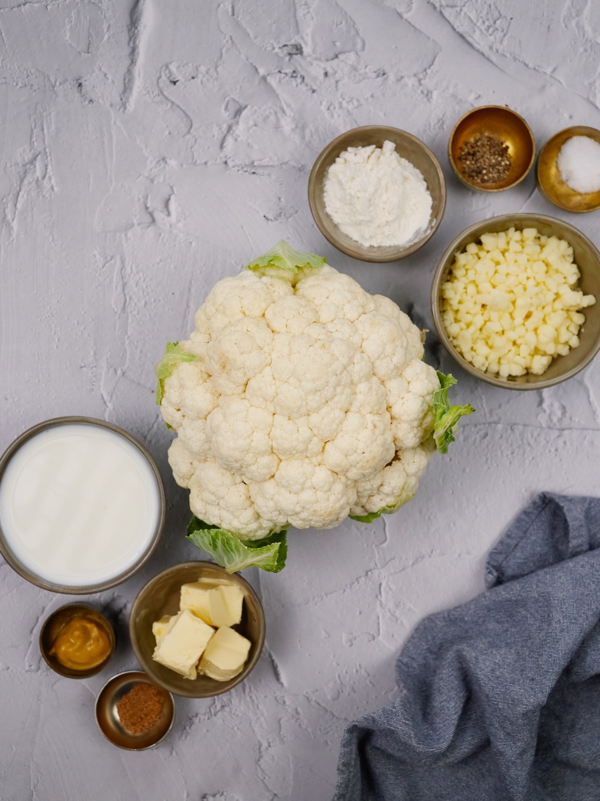 ingredients for cauliflower casserole in small bowls on a white surface