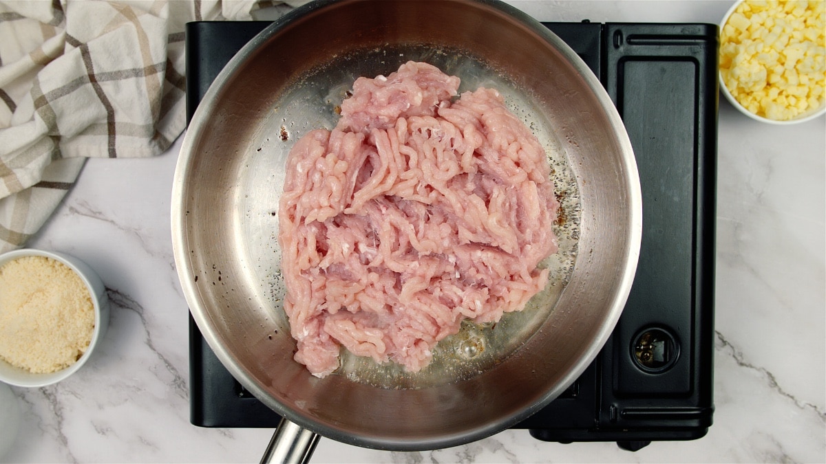 raw ground chicken in a pan on a stove top