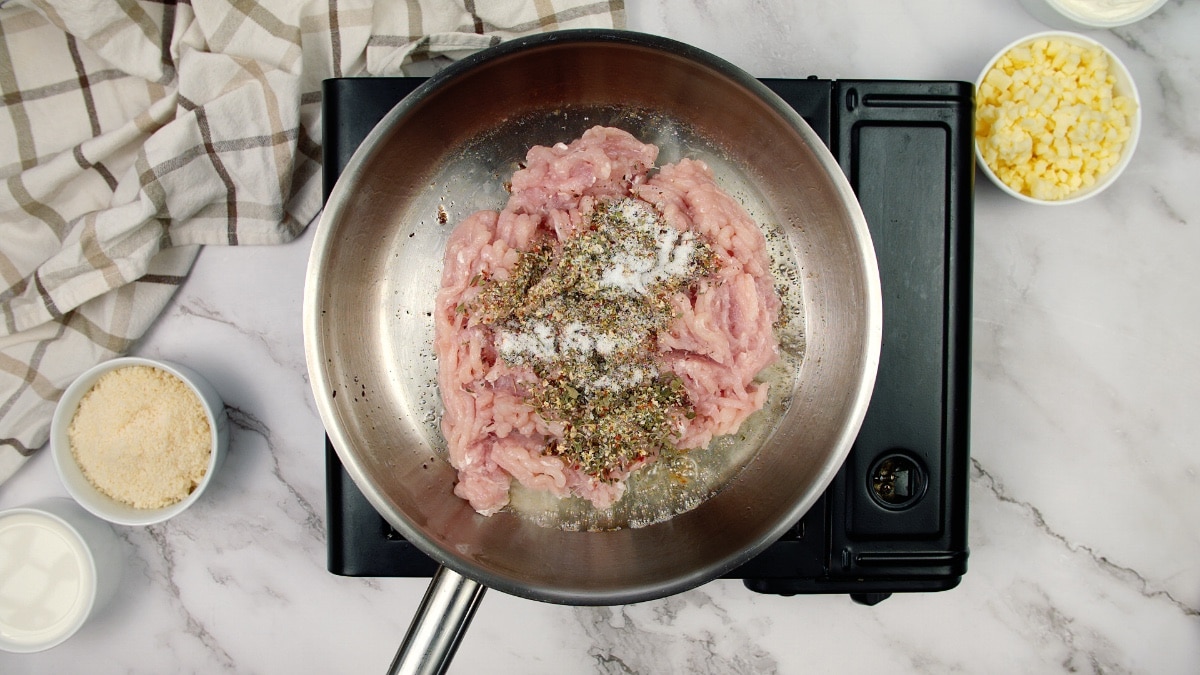 raw ground chicken topped with seasonings in a pan