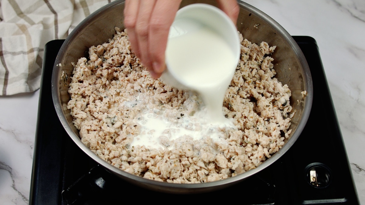 cooked ground chicken in a pan being topped with cream
