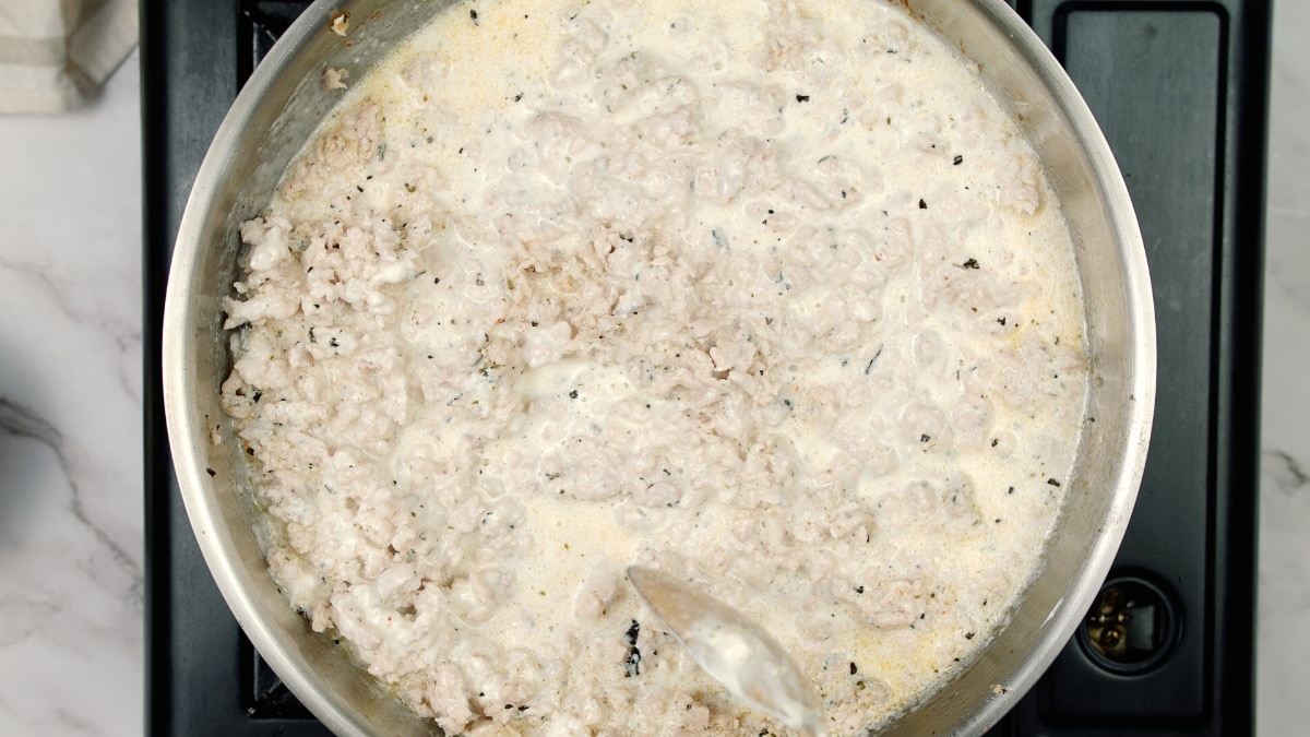 simmering liquid and cooked ground chicken in a pan