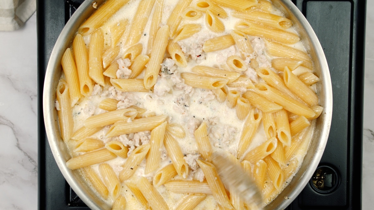 penne pasta being cooked in the pan with the other ingredients