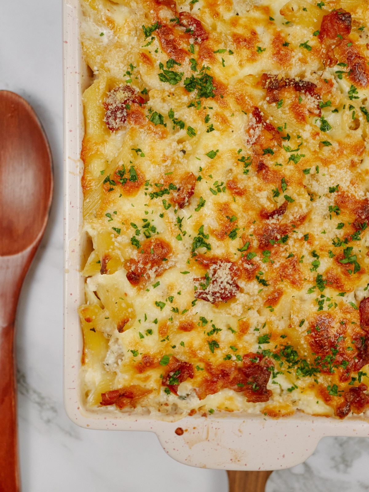 Chicken bacon ranch casserole baked in a dish and topped with bacon pieces and chopped parsley