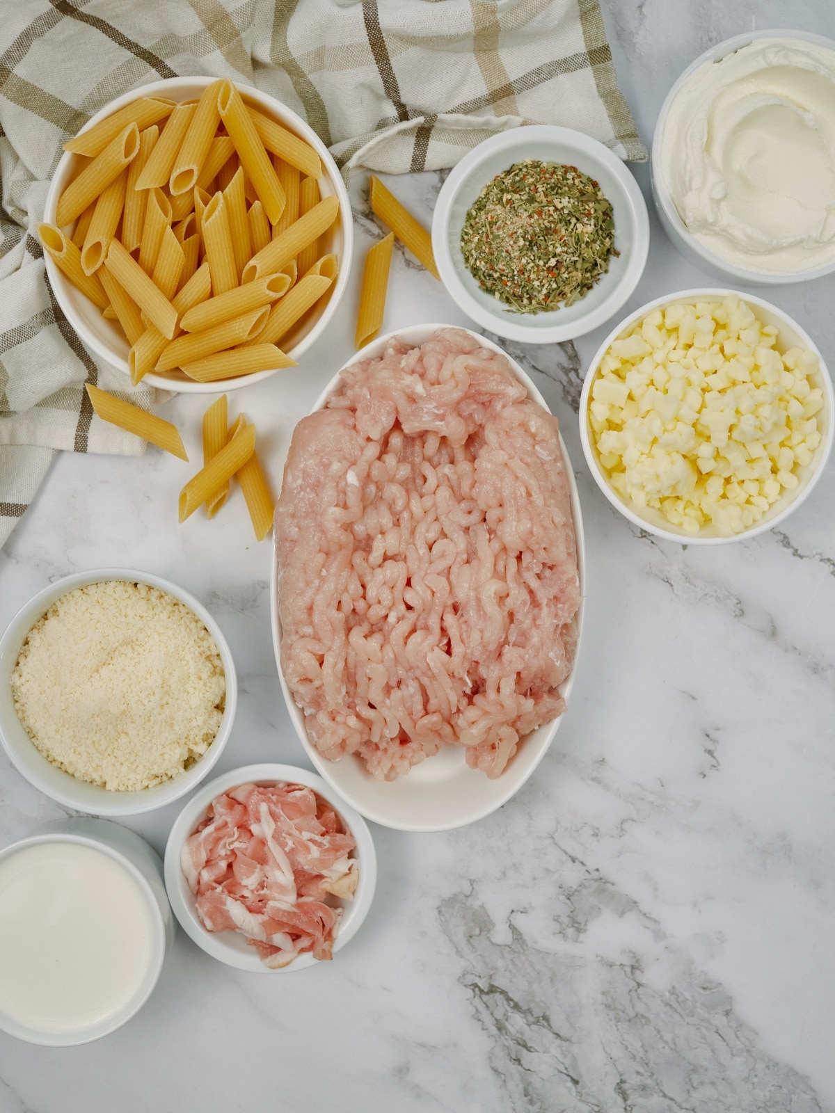 ingredients for chicken bacon ranch casserole in bowls on a white surface