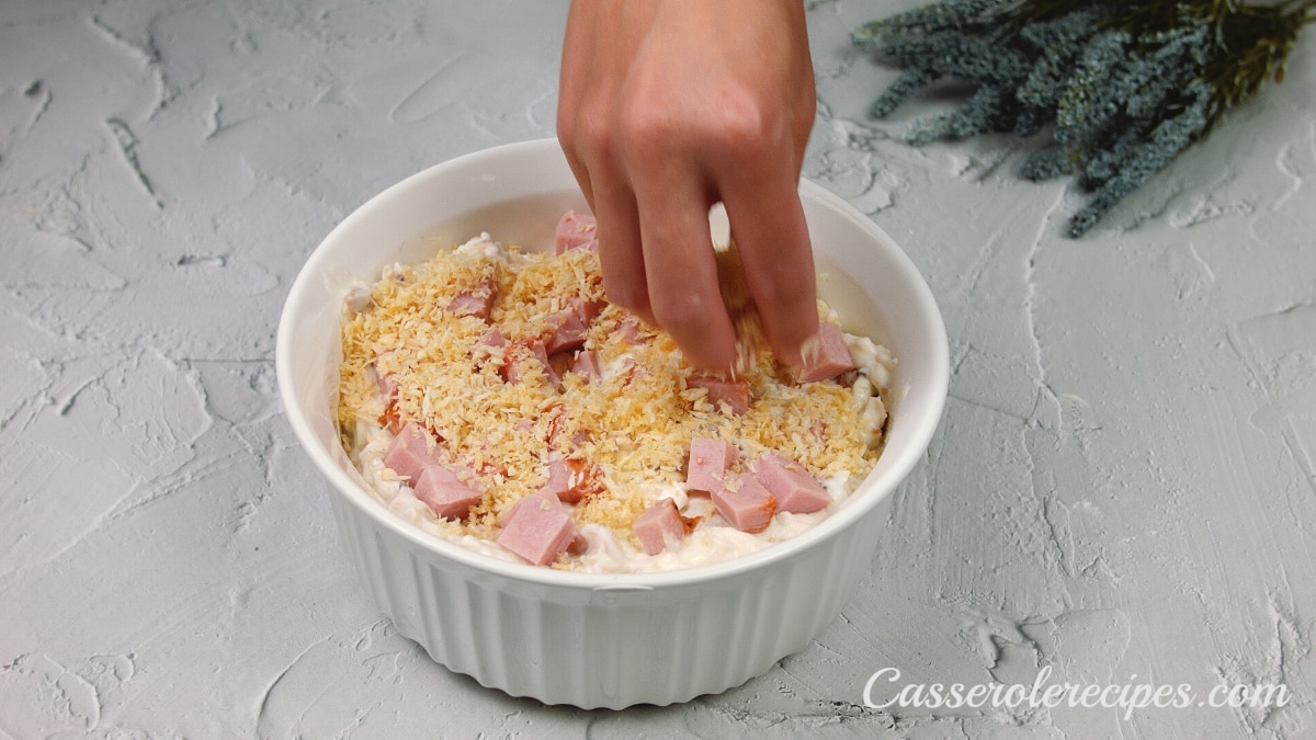 topping a baking dish full of casserole with breadcrumbs