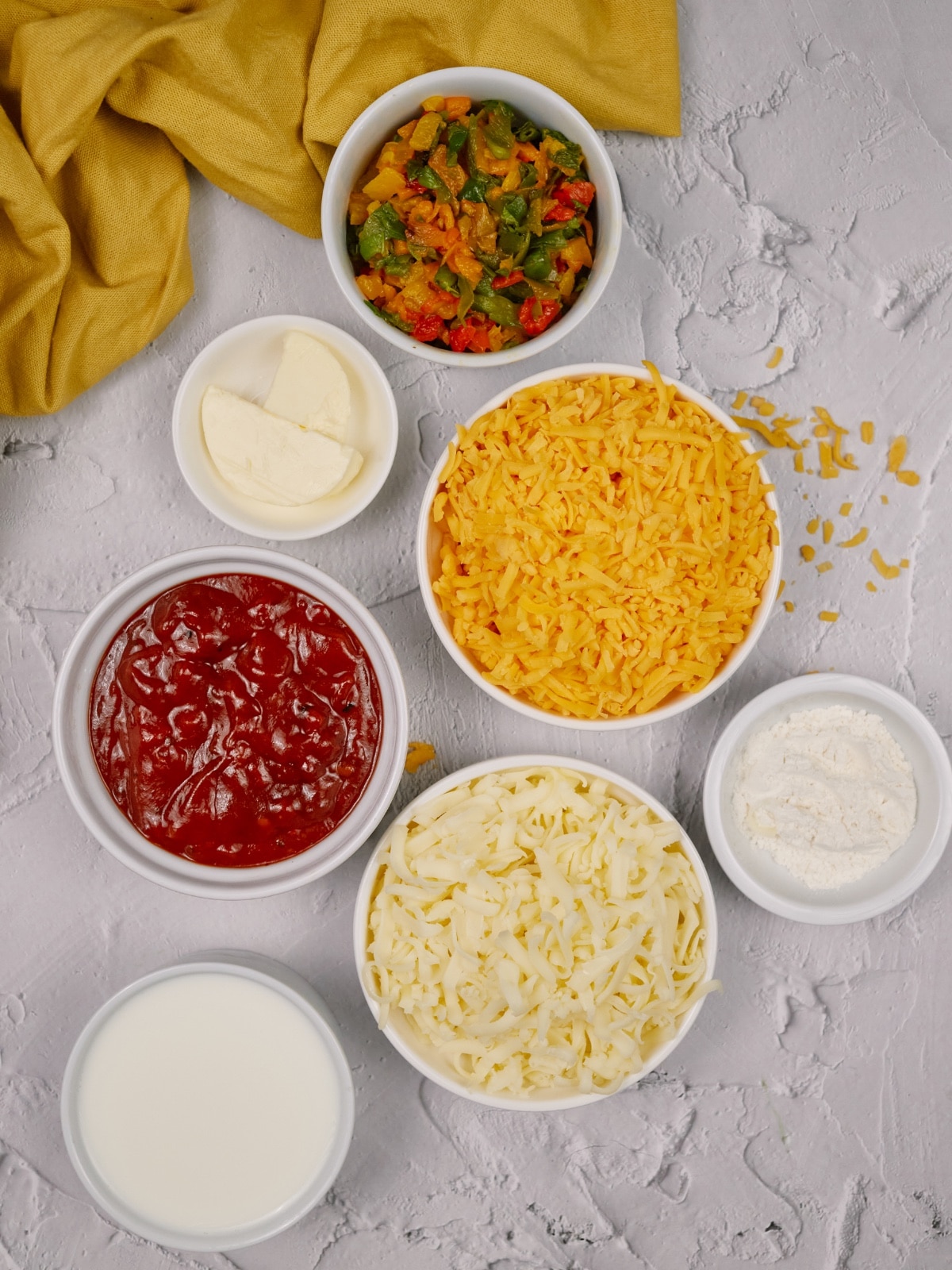 ingredients of chili relleno casserole in small white bowls on a white surface