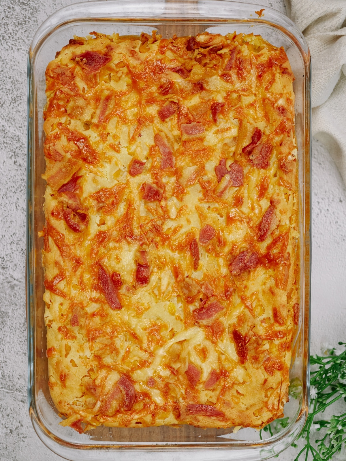 an overhead view of baked cornbread casserole in a glass baking dish