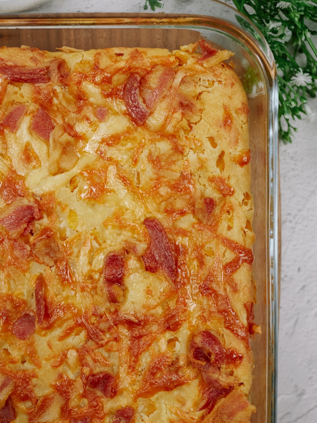 an overhead view of baked cornbread casserole in a glass baking dish