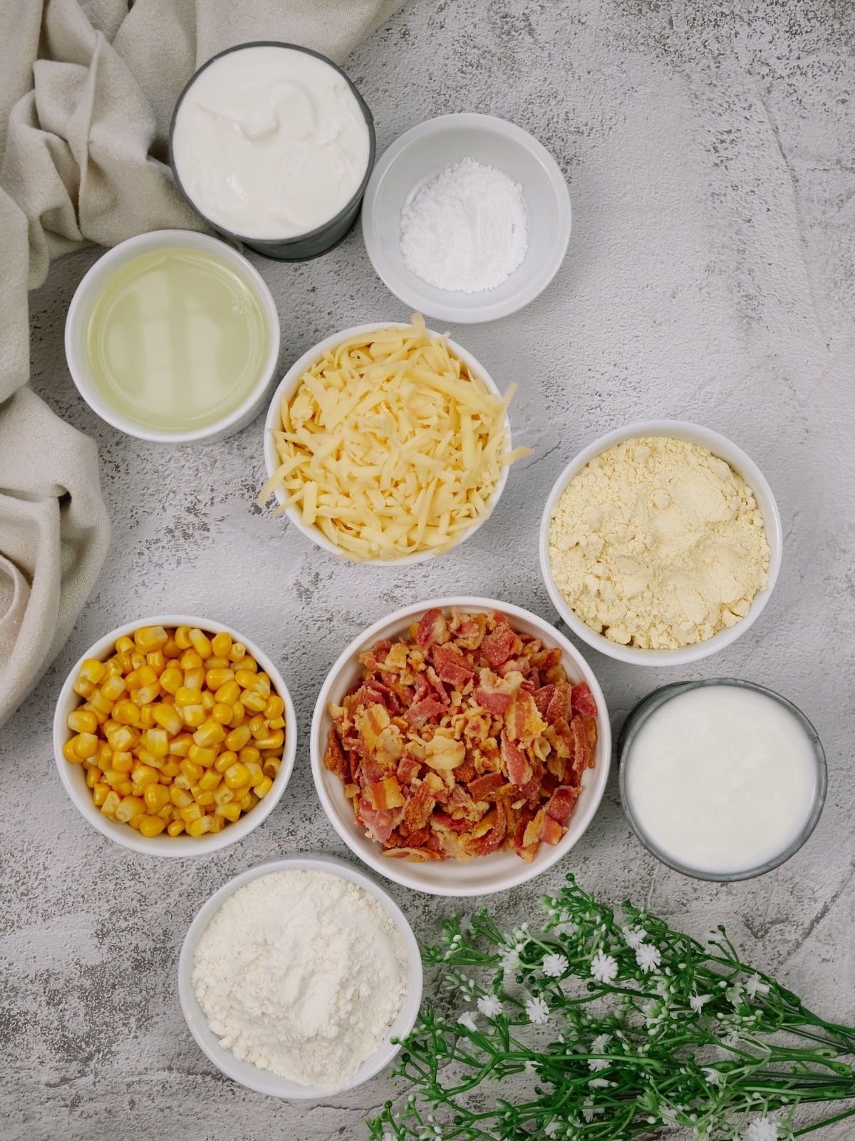ingredients for cornbread casserole in bowls on a white surface
