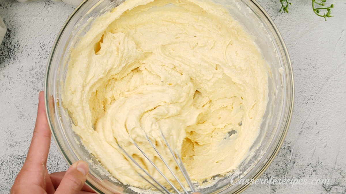 mixing a thick batter together in a glass bowl with a whisk
