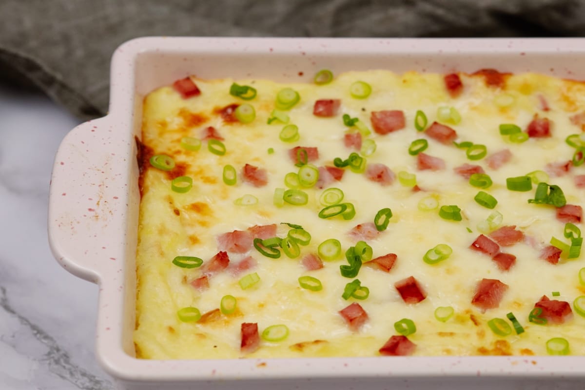 baked potato casserole topped with bacon bits and green onions 