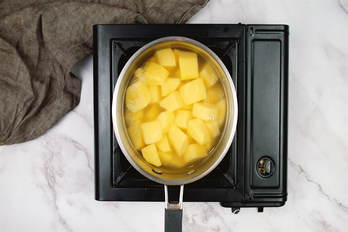 cubed potatoes boiling in a pot of water on a stovetop 