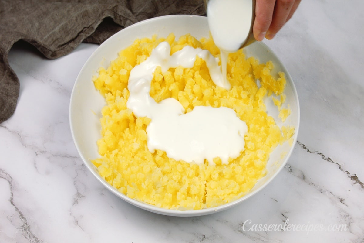 pouring sour cream over the mashed potatoes