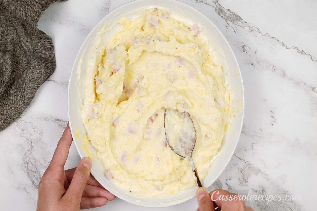 smoothing the surface of mashed potatoes with a spoon in a bowl