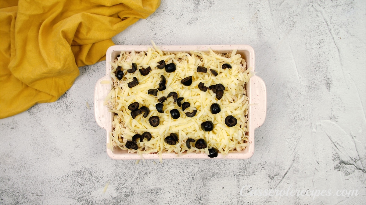 a casserole dish topped with black olives on a white surface