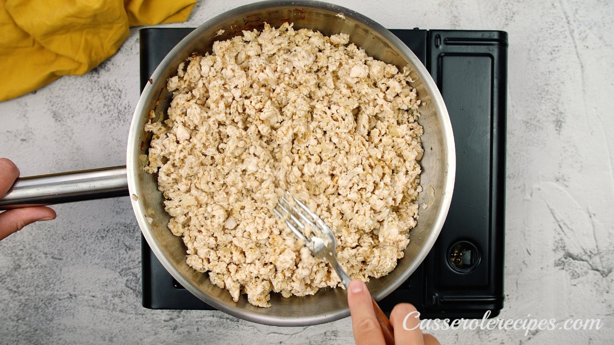 cooked ground chicken in a saute pan being mixed with a fork