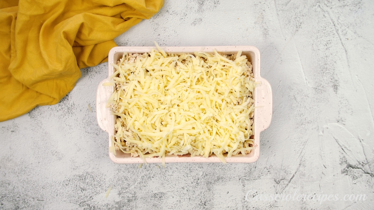 a casserole dish topped with shredded cheese on a white surface