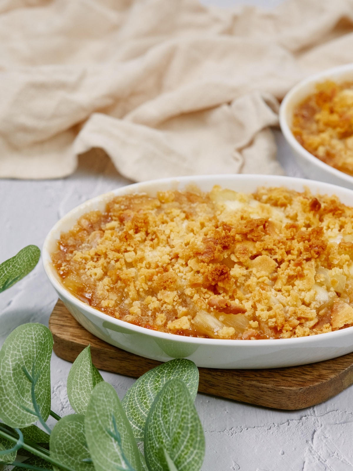 pineapple casserole in a white baking dish on a cutting board and white surface