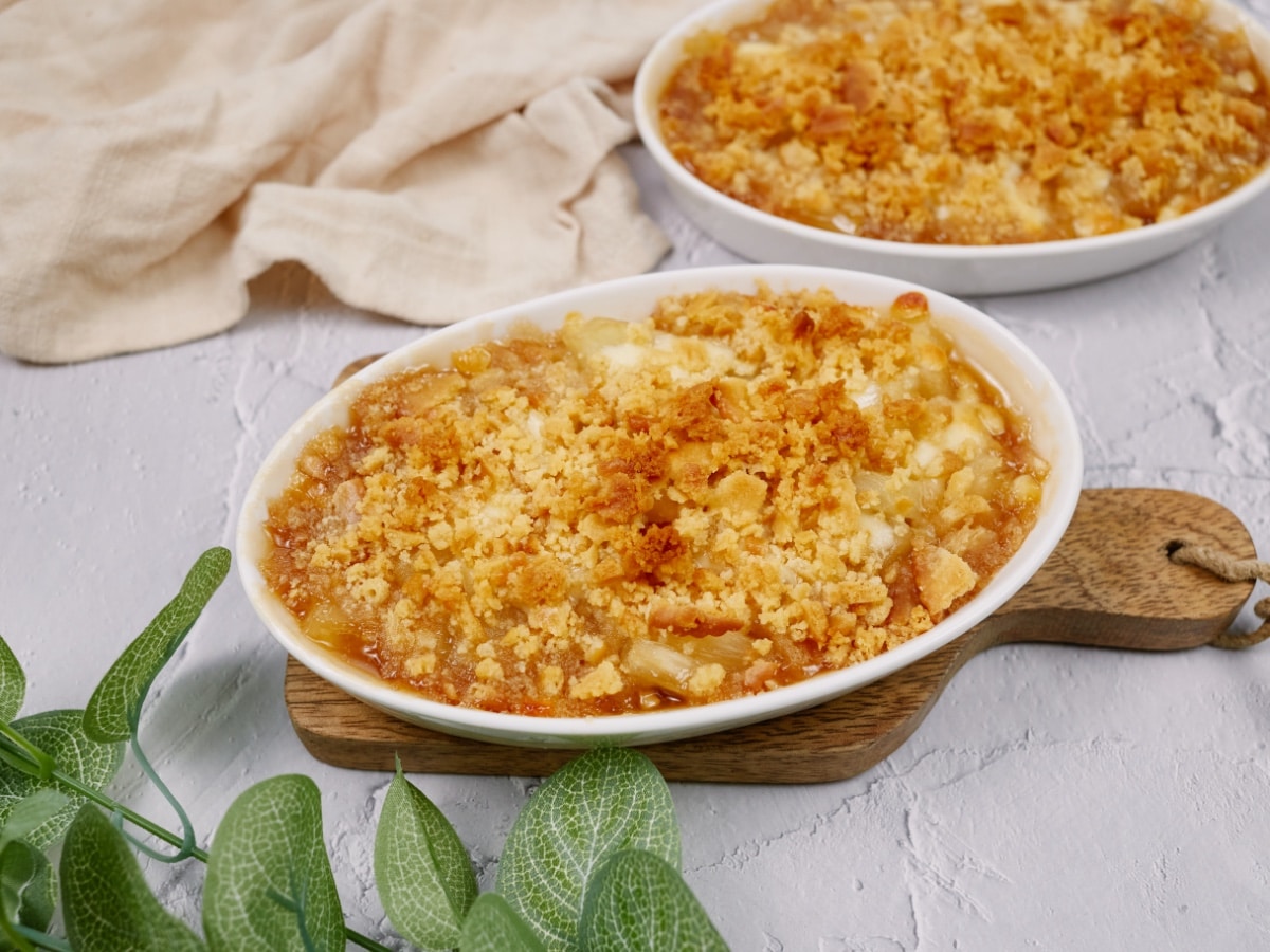 pineapple casserole in a white baking dish on a cutting board and white surface