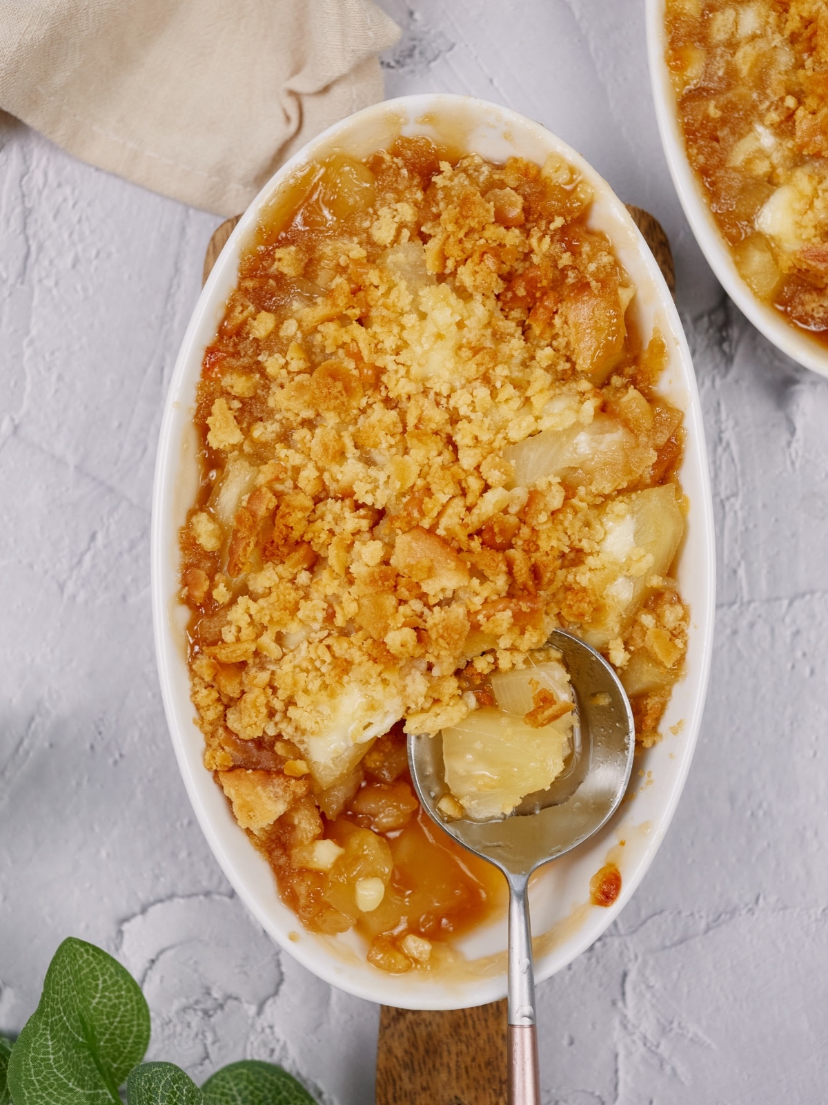 pineapple casserole in a white baking dish on a cutting board and white surface