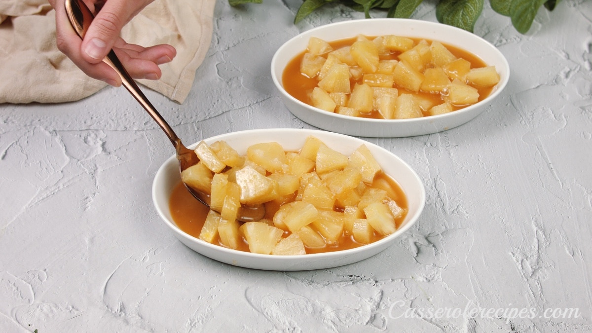 placing the pineapple mixture in two small bowls with a spoon