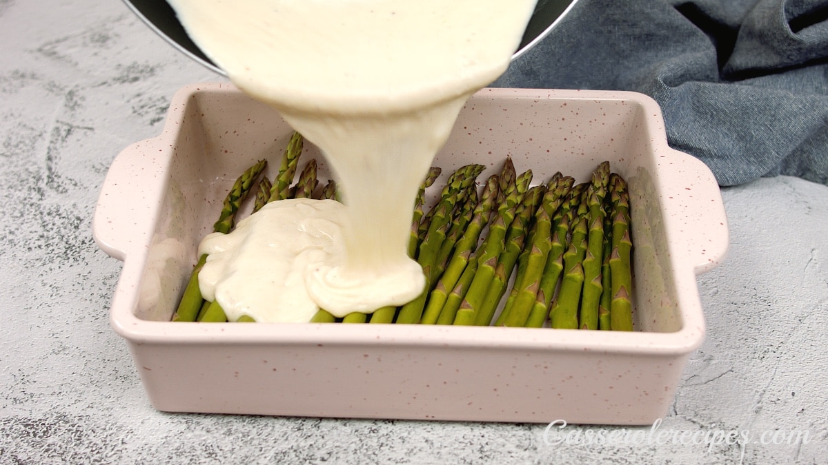 sauce being poured over asparagus