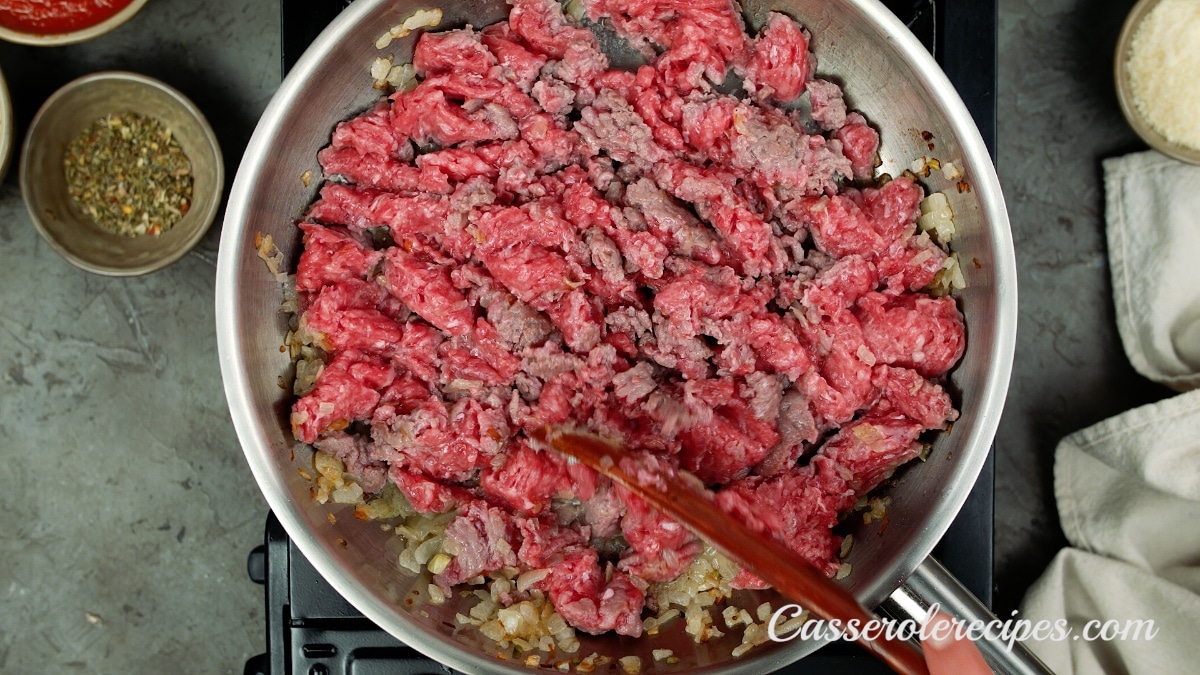 stirring beef in pan with a wood spoon