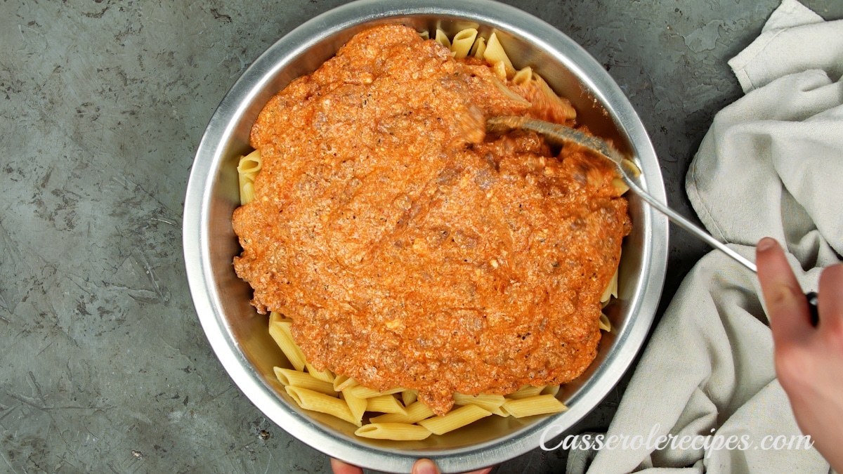 the tomato sauce poured over penne pasta in a bowl