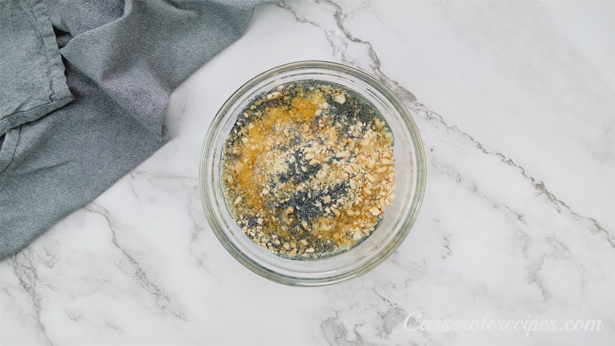 olive oil poured into poppy seeds and breadcrumbs in glass bowl