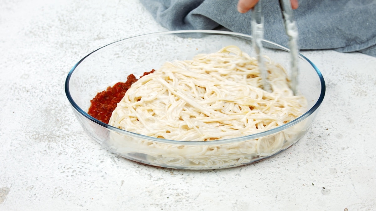 spaghetti spread over the meat mixture in the baking dish