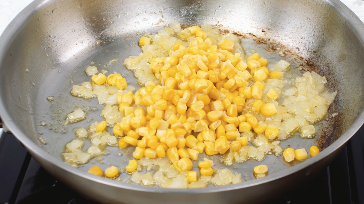 corn added to the onions and garlic in pan