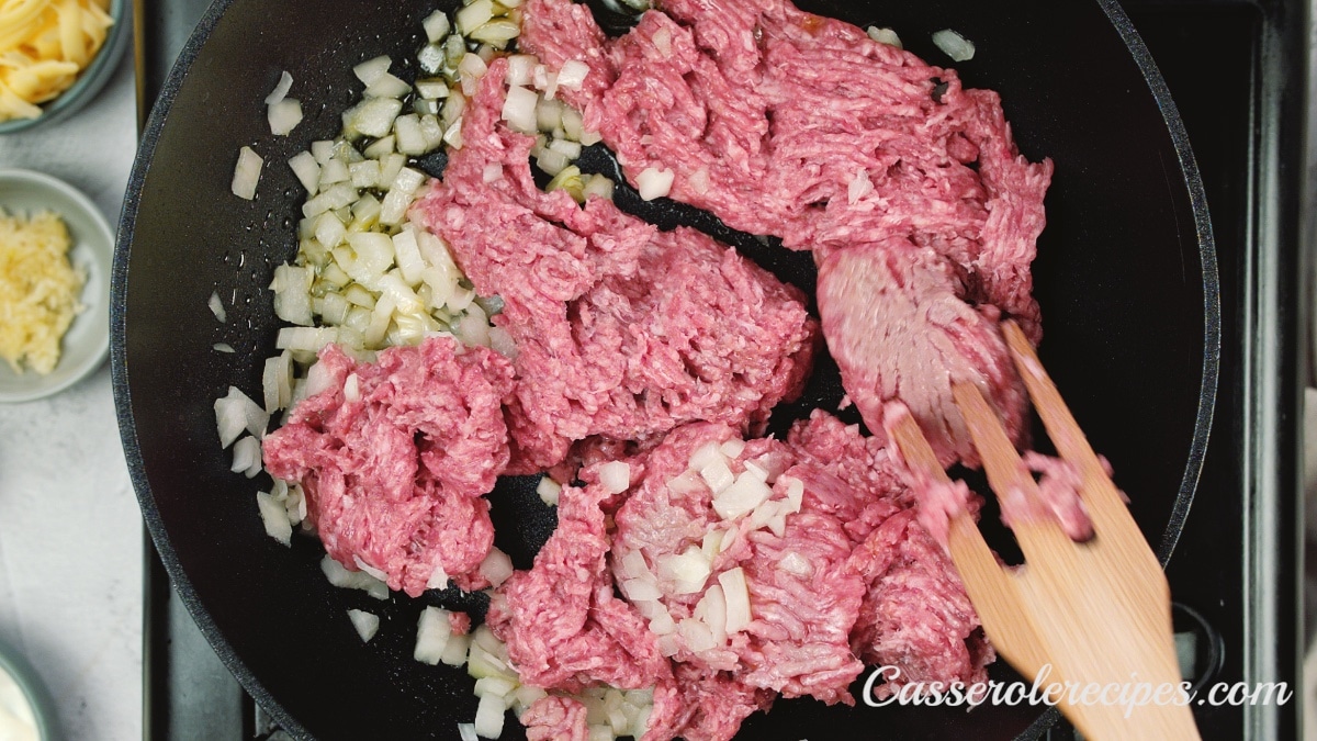 stirring beef in skillet with a fork