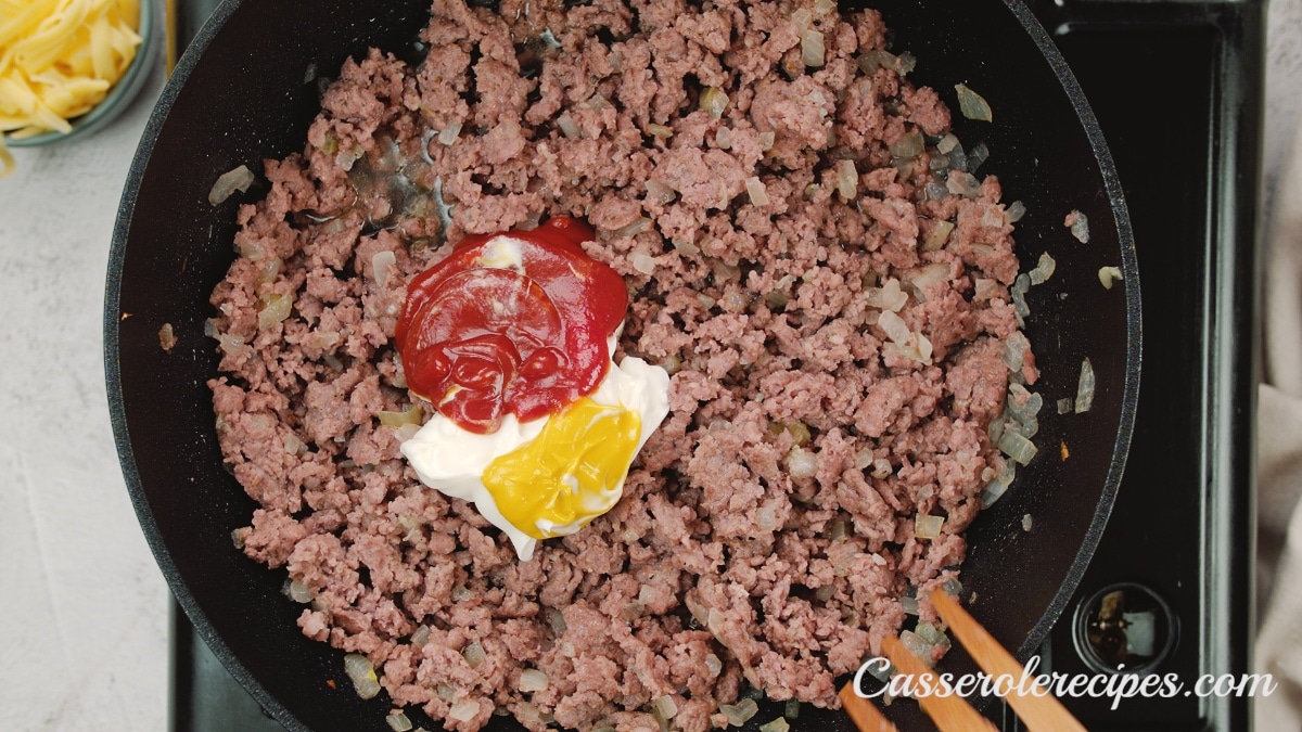 ketchup, mayonnaise, and mustard on top of beef in skillet