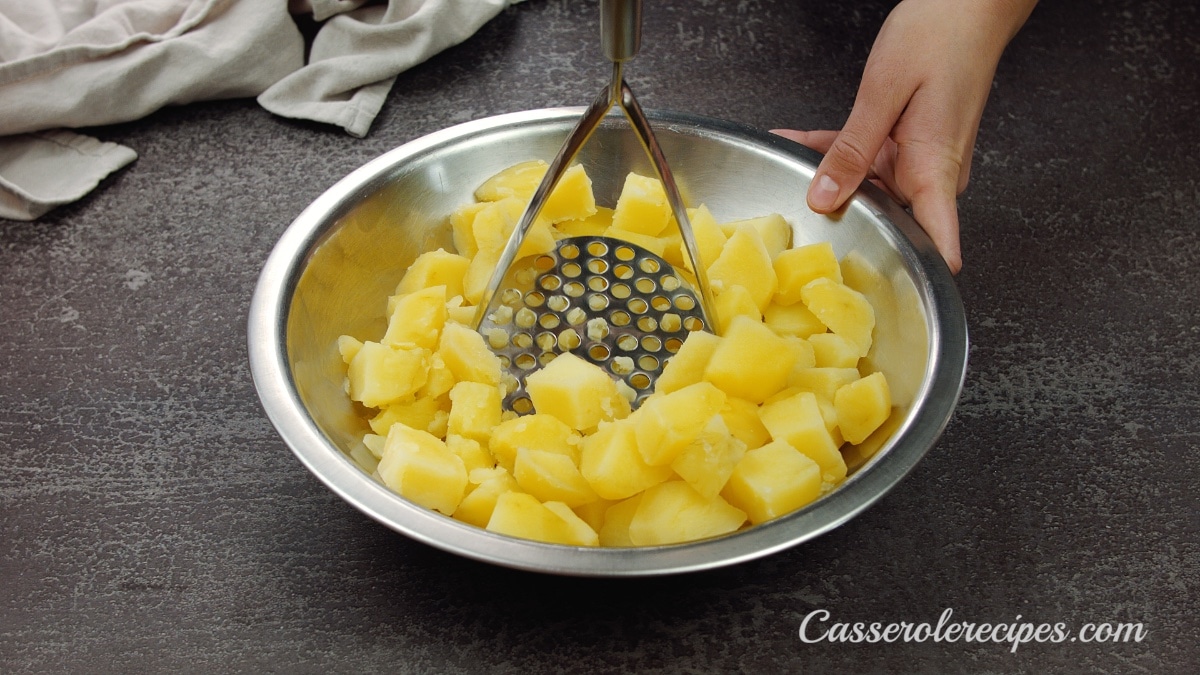 mashing potatoes in a metal bowl