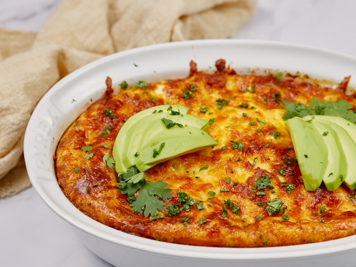sausage breakfast casserole in a baking dish topped with parsley and avocado slices