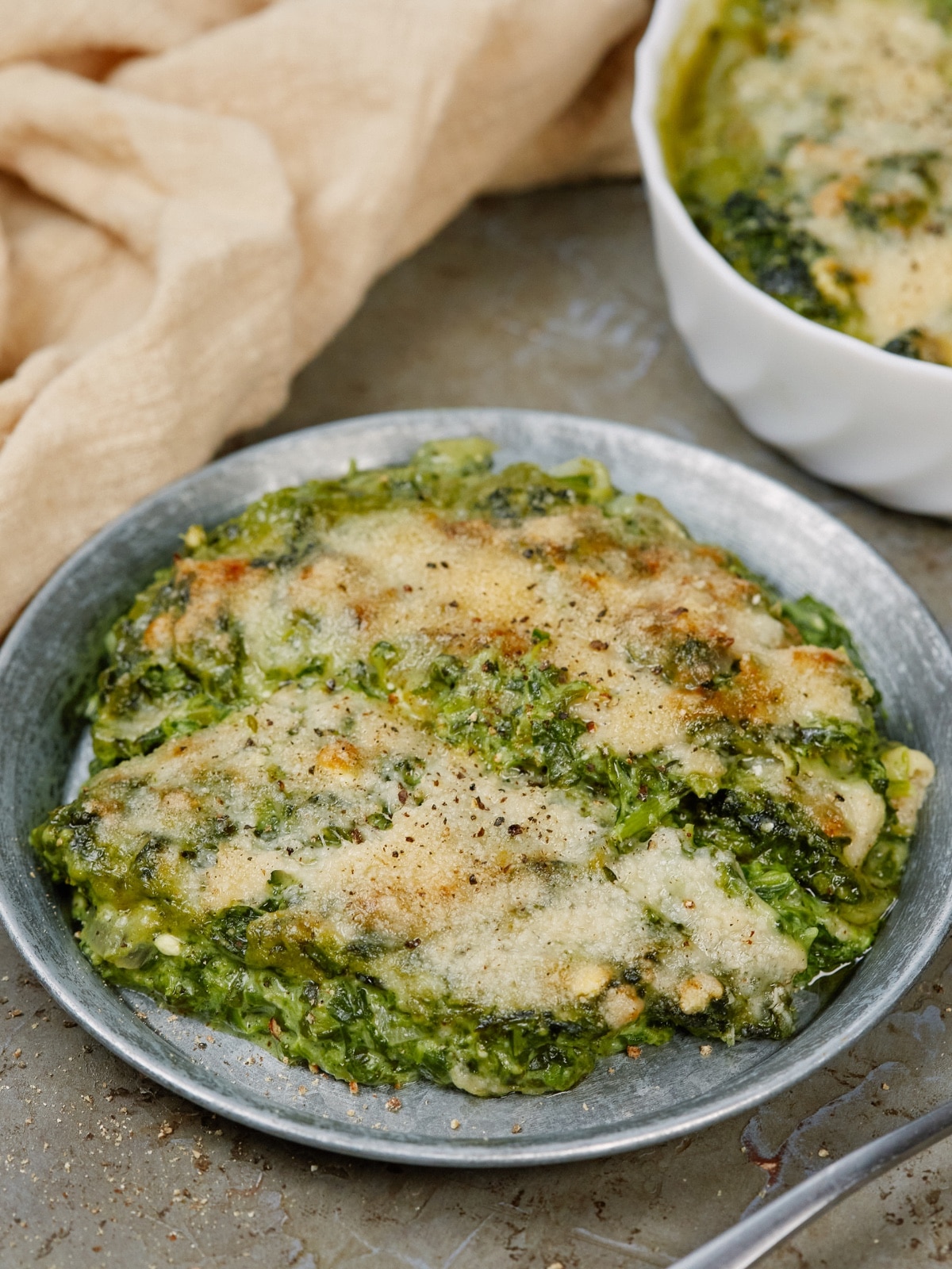 spinach casserole serving on a gray plate