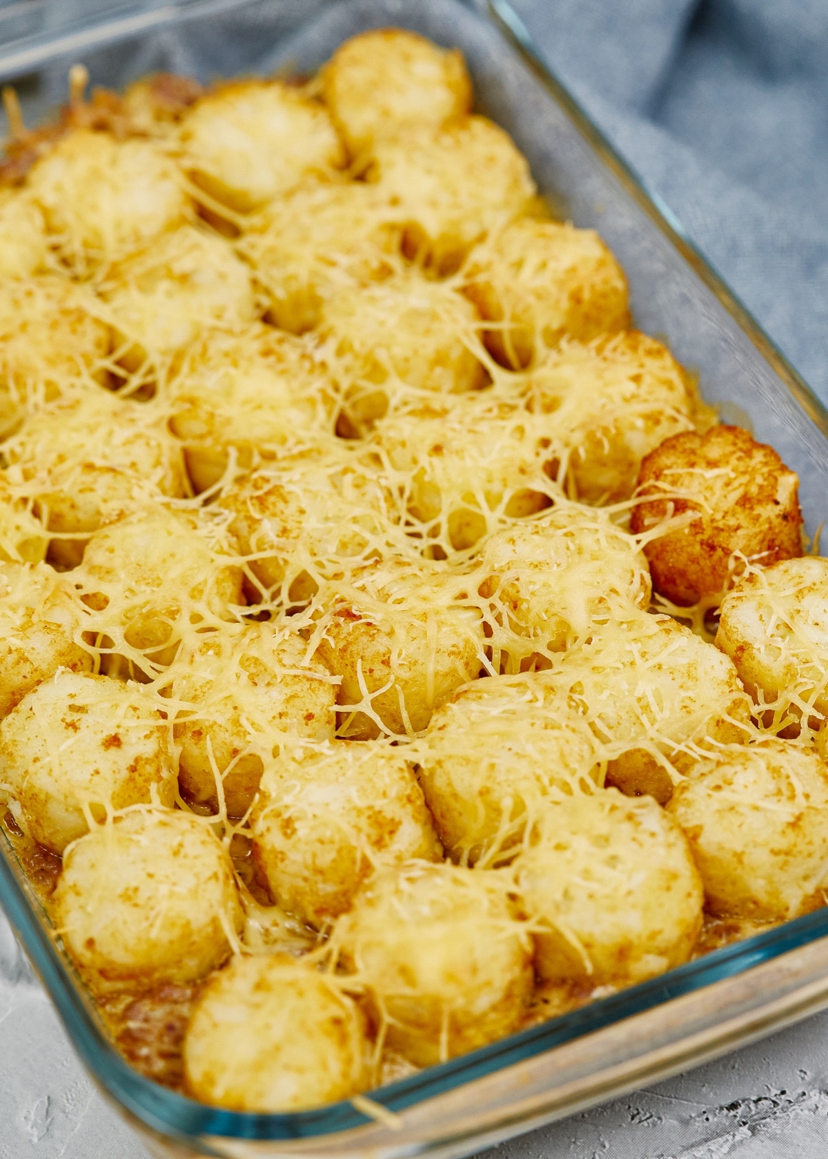 tater tot casserole in a baking dish topped with cheese