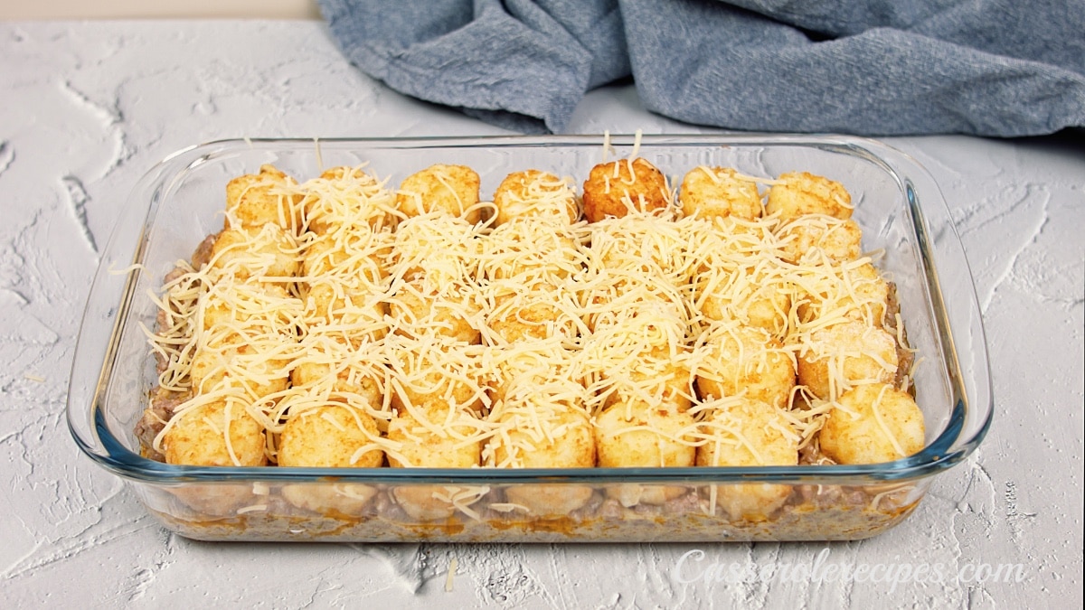 unbaked tater tot casserole topped with cheese