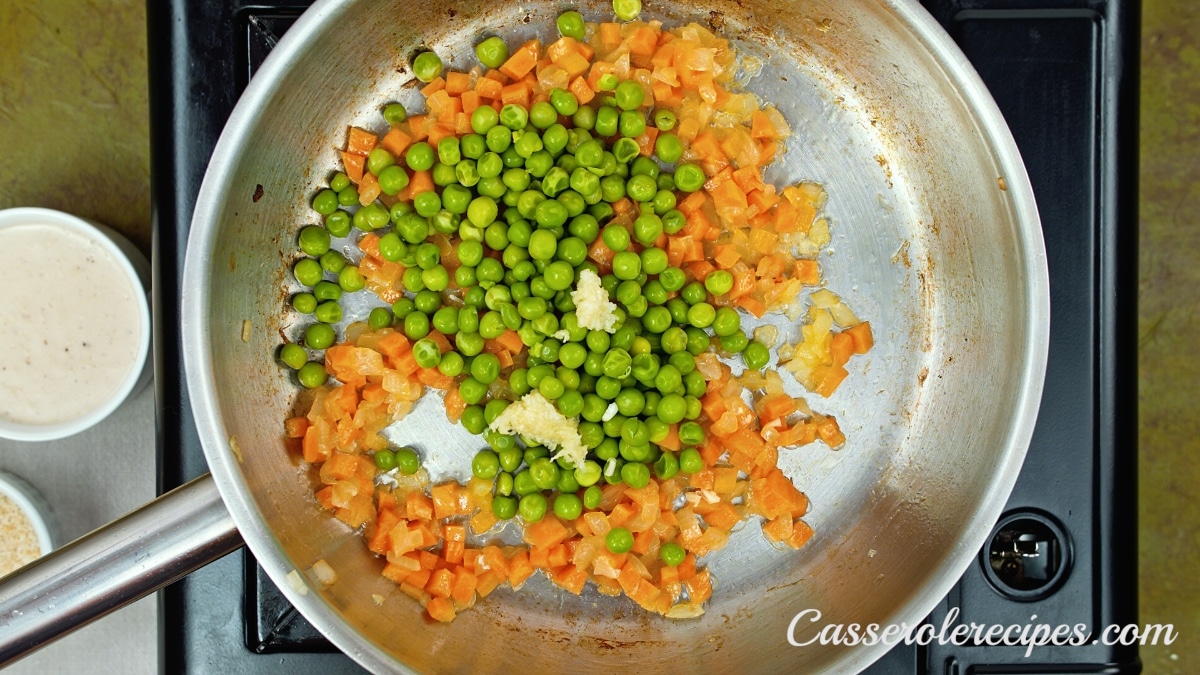 garlic, peas, carrots, and onions, in a pan on the stovetop