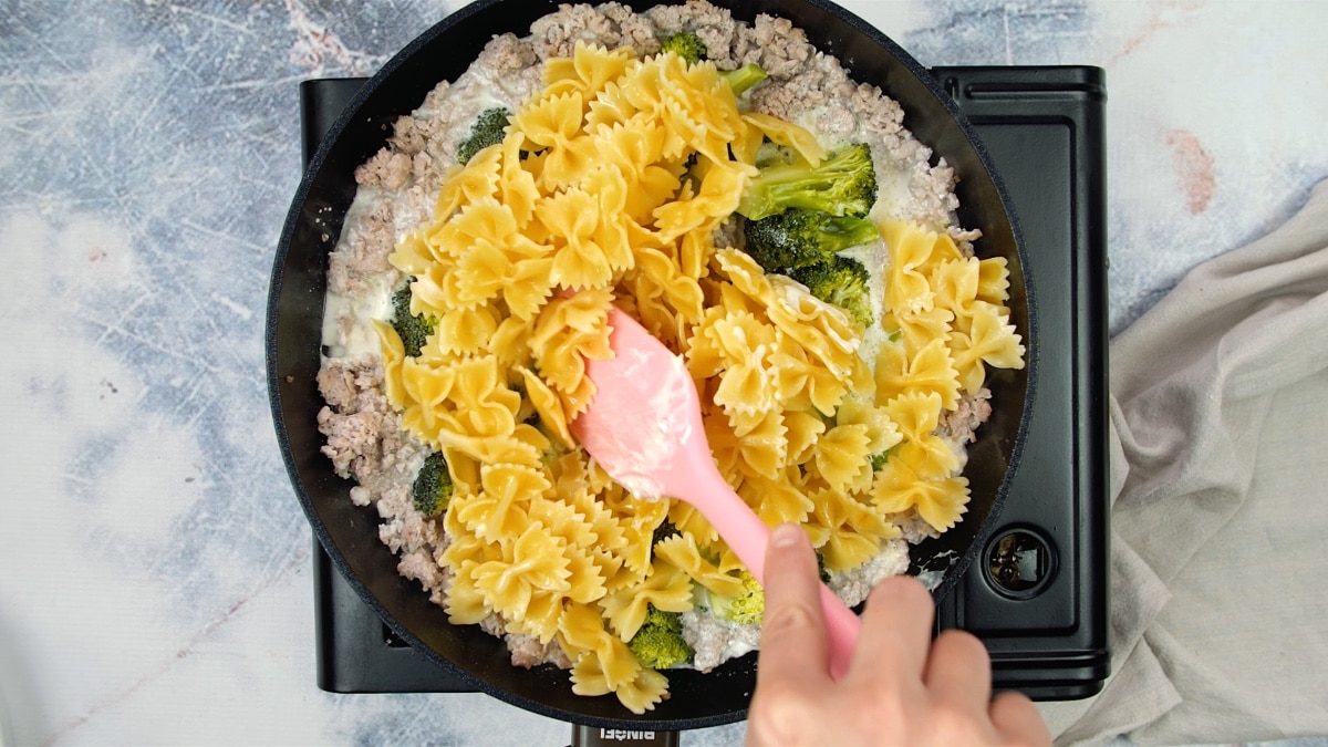 pasta added to meat and broccoli in skillet