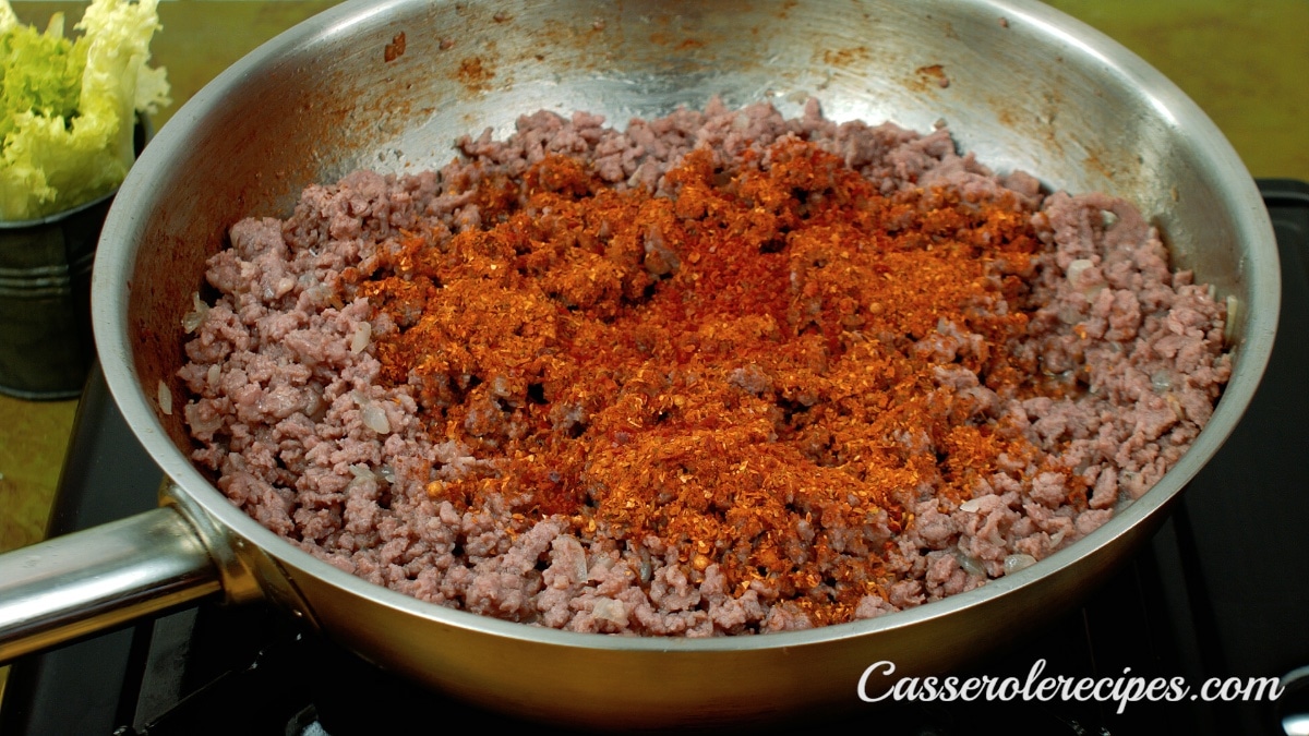 seasonings added to ground beef in a pan