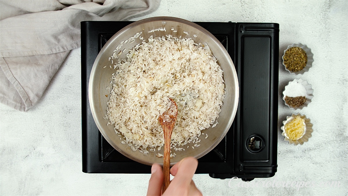 stirring rice into onions in pan