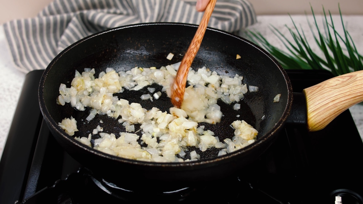 stirring onions in pan with a wooden spoon