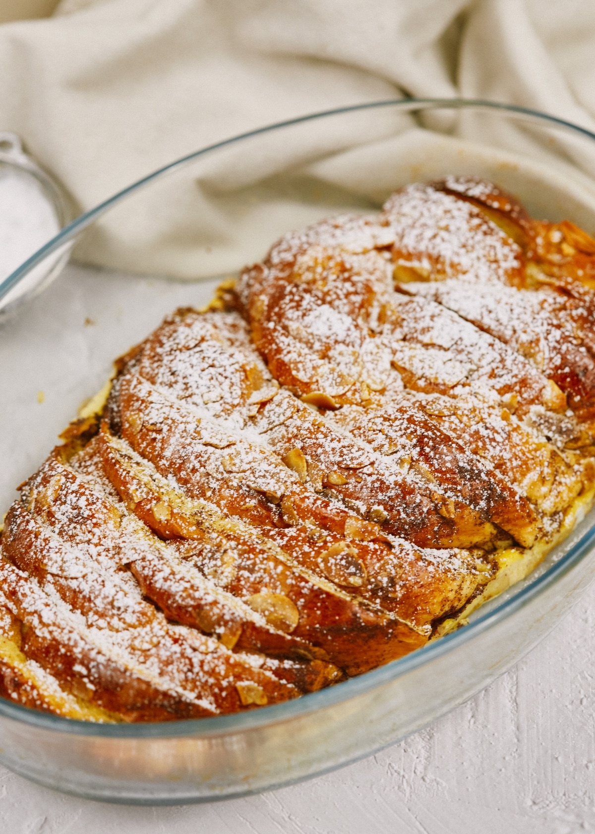 french toast casserole sprinkled with powdered sugar in baking dish