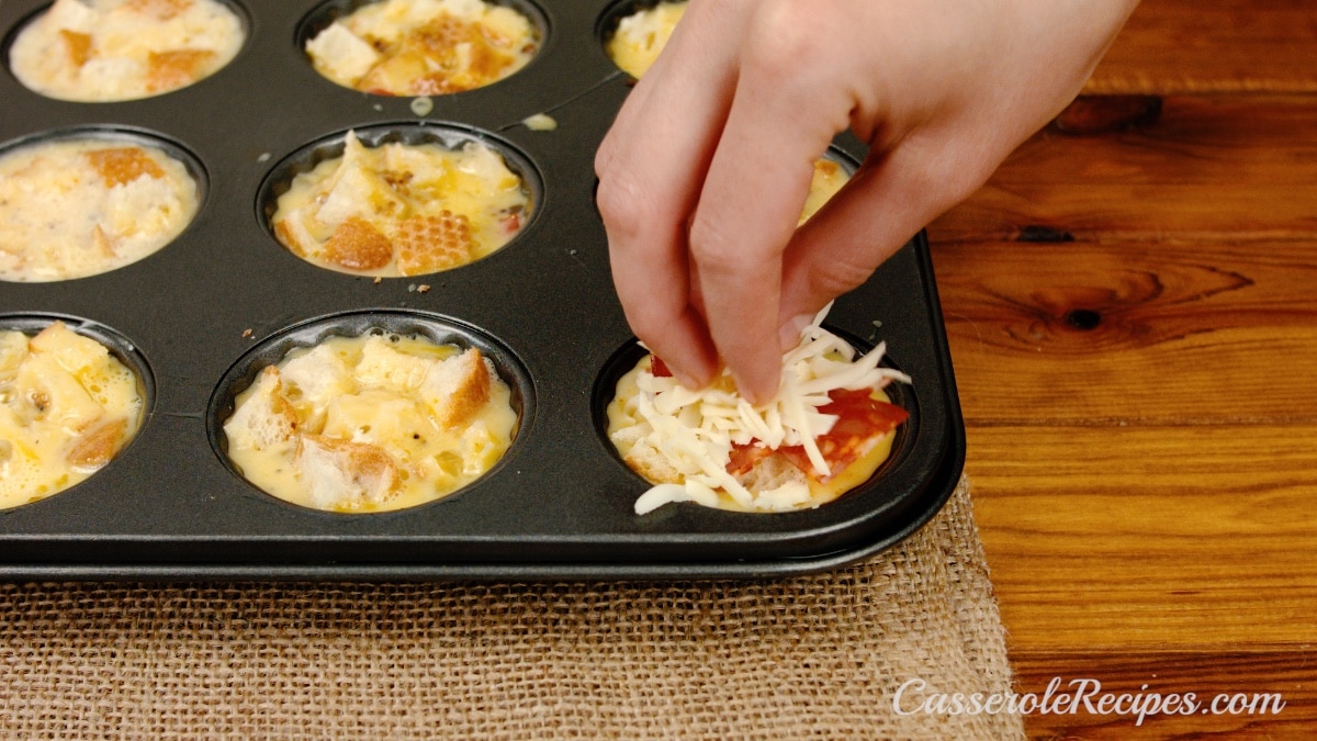 sprinkling cheese over muffin tin egg mixture