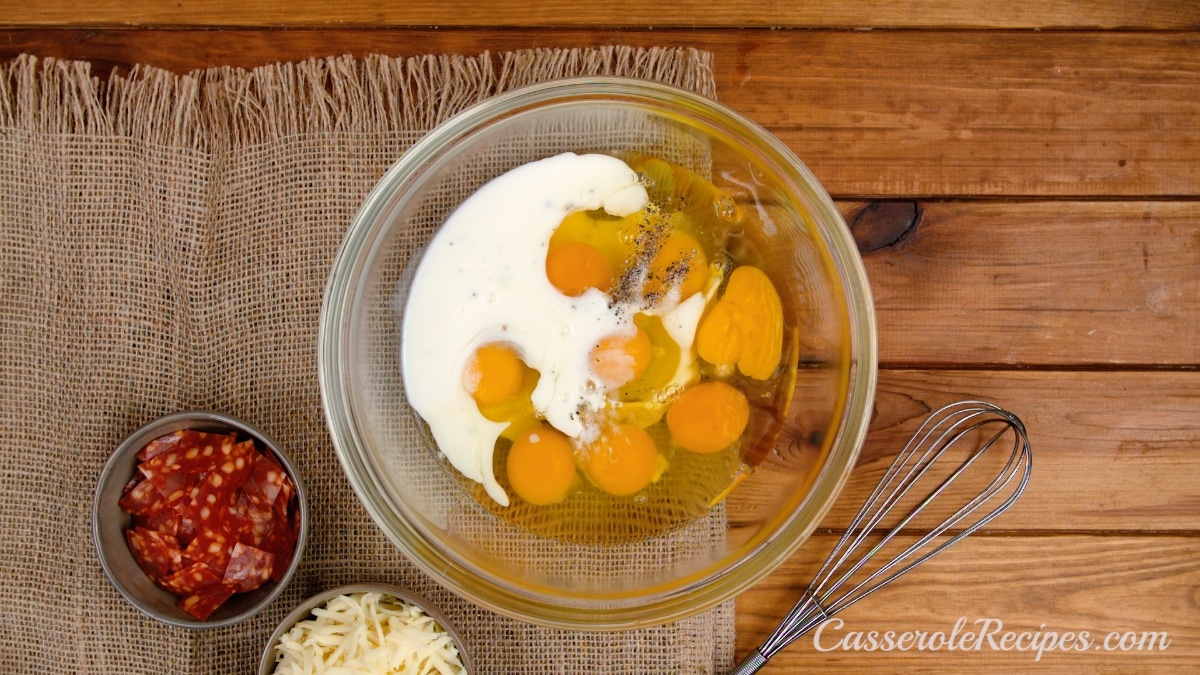 milk added to eggs in glass bowl